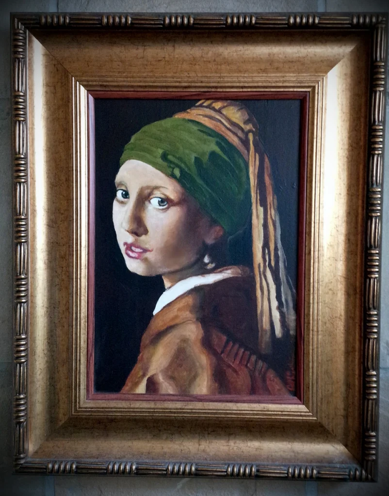 Framed painting of a girl in a green turban looking over her shoulder, after Vermeer